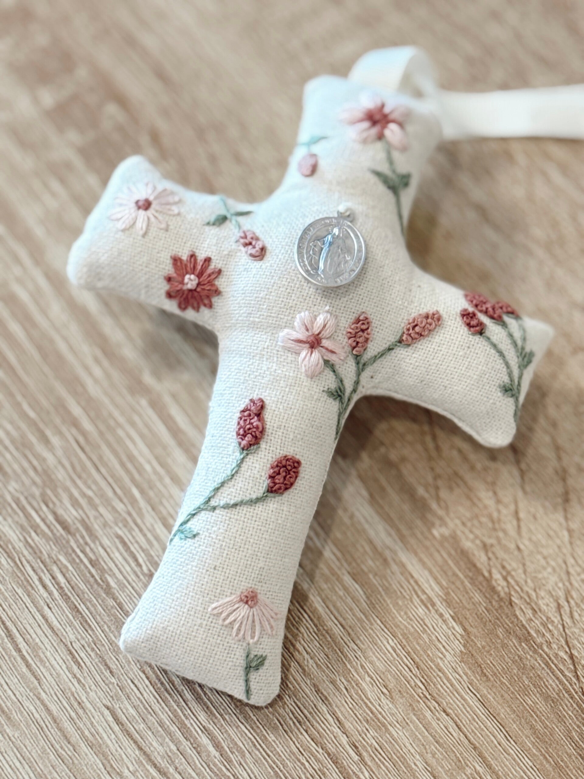Cruz de tela “Jardín de flores” con medalla