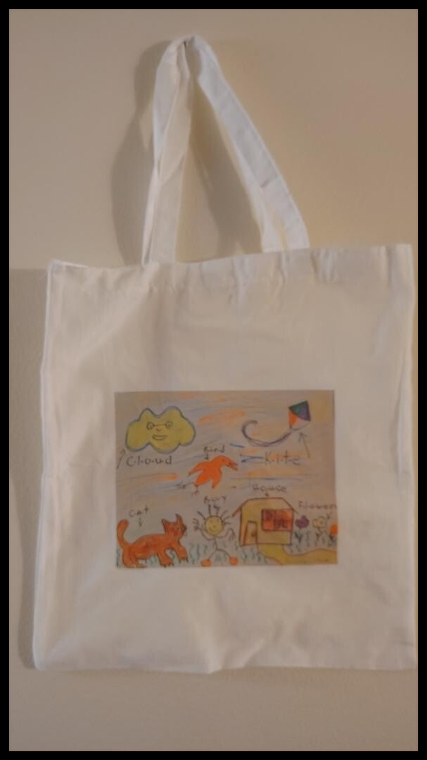 A white tote bag measures 15 inches long and is 14 inches wide the image callwd a kida happy home