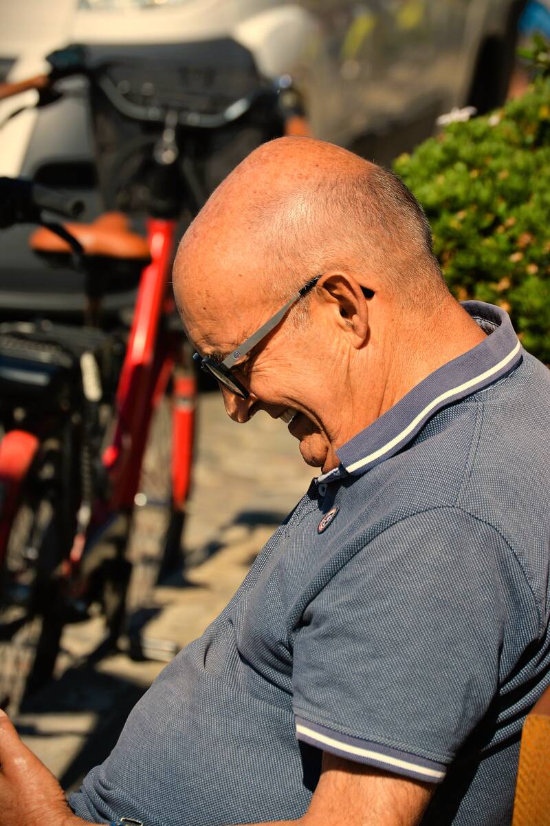  c'est le portrait d'un homme assis sur un banc qui sourit en regardant son téléphone portable
