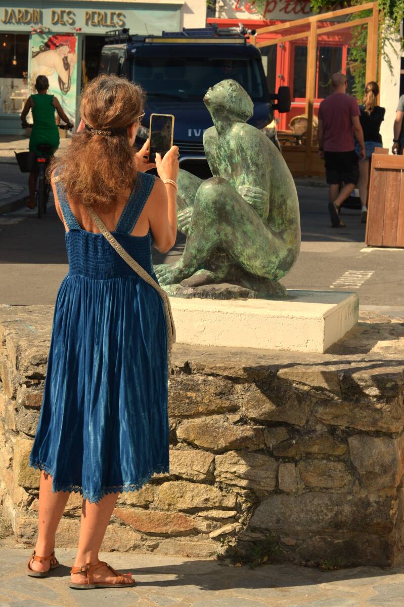 c'est la photo d'une femme de dos qui prend une photo d'une statue