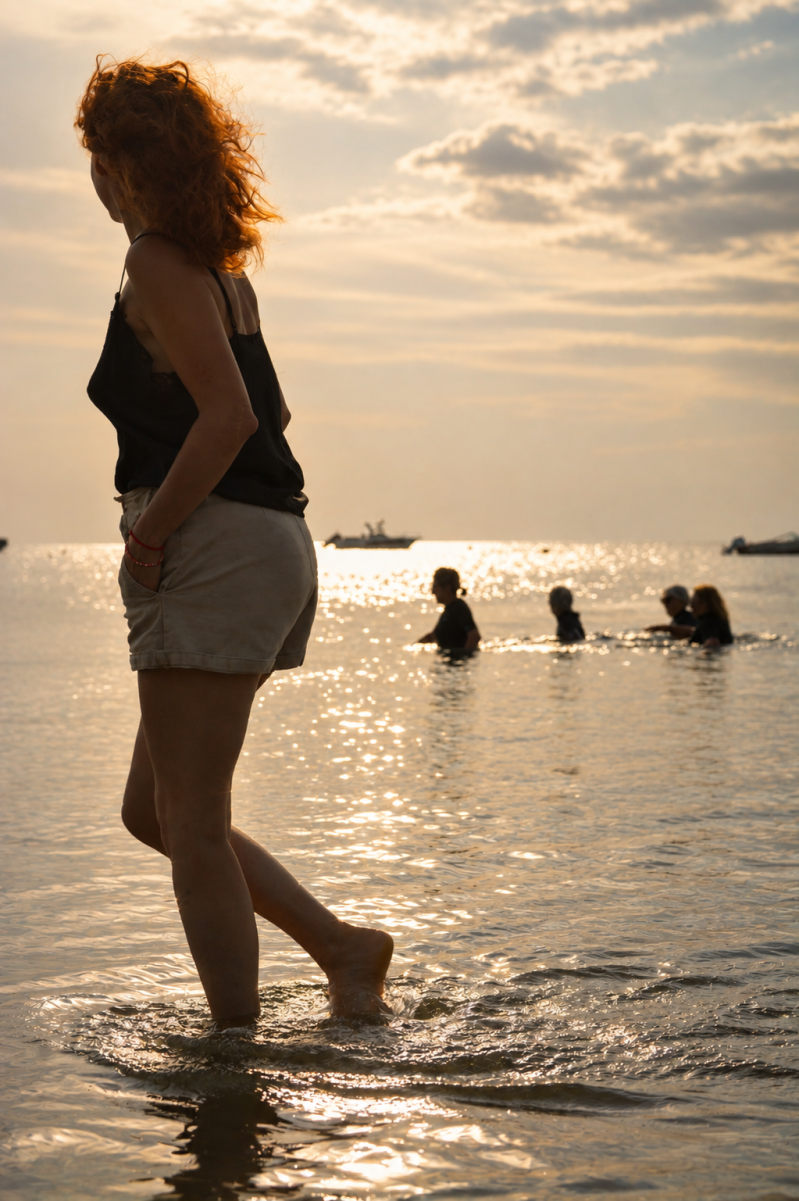 photo d'une femme rousse qui marche le long de la plage devant d'autres femmes qui font du longe côte