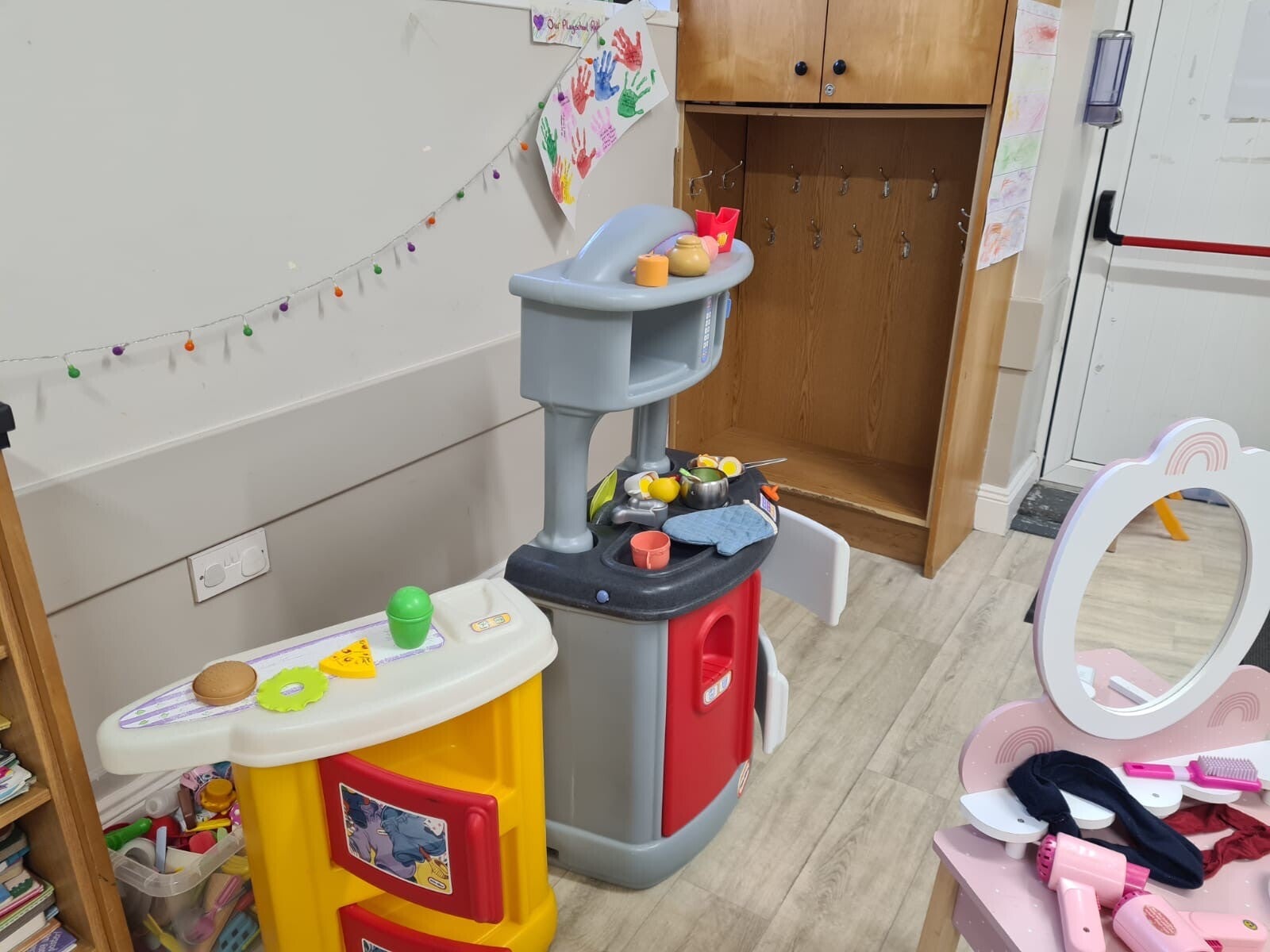 A view of a part of Room 1 where there is a toy kitchen and toy dressing table with mirror