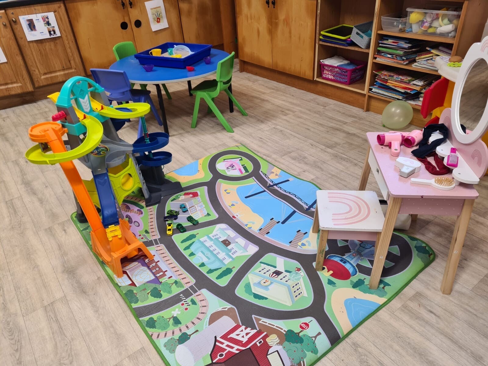 Another view of Room 1 with a toy car roller coaster and a road play mat alonside the dressing table and stool.