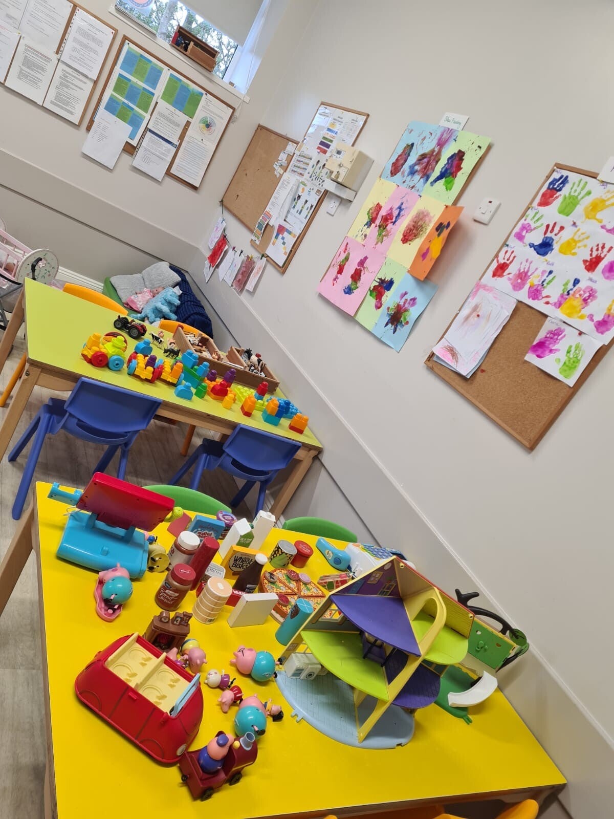 A view of 2 tables with play displayed on them, one with duplo lego and the other with Peppa Pig toys.