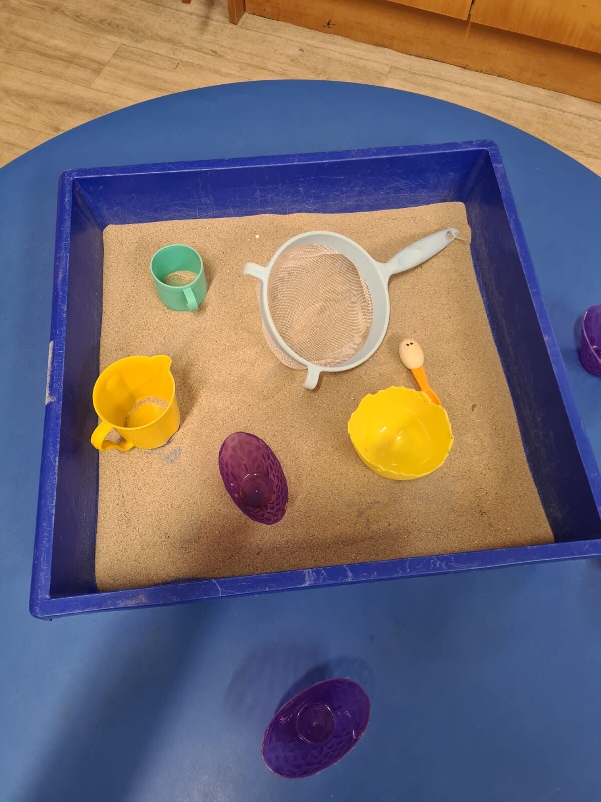 A sand tray with beakers and cups and other vessels.