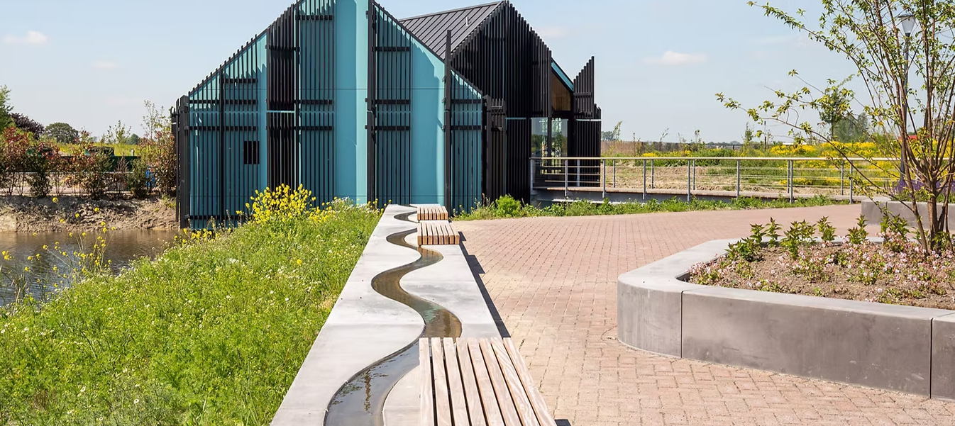 Een rustig uitvaartcentrum met een groene tuin, bloemen en bomen rondom het gebouw, wat bijdraagt aan een serene en rustige sfeer.