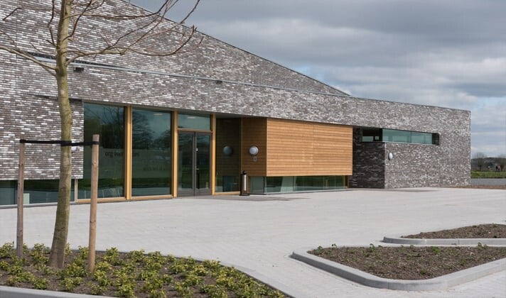 Modern gebouw met stenen voorpui in combinatie met houten afwerking.