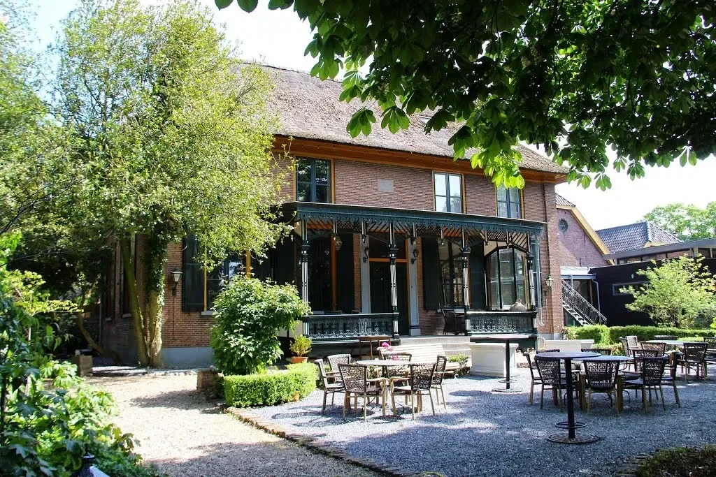 Karakteristiek herenhuis met authentieke veranda en lommerrijk terras, omringd door groen – charmante en serene locatie voor een persoonlijke uitvaart of levensviering in de buitenlucht.