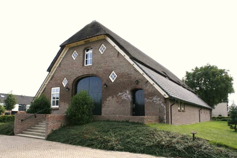 Een Vloedschuur met krakateristeiek kap geleghen op een verhoogde heuvel.