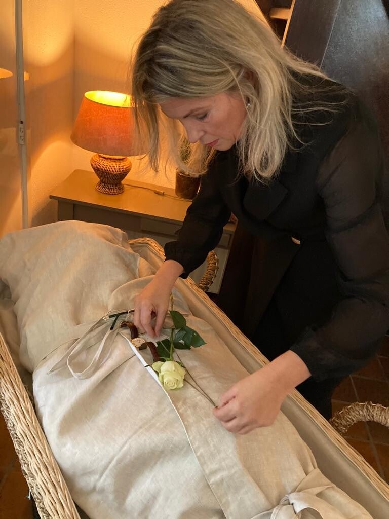 Uitvaartverzorger bij lijkwade met overledene op een opbaarplank.