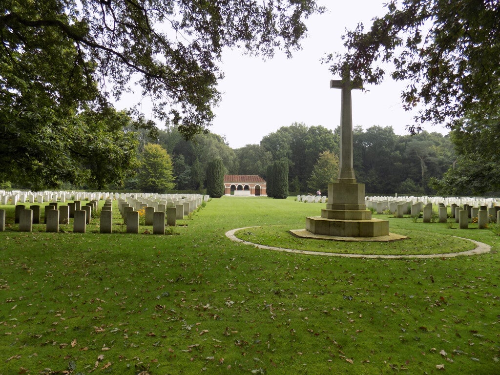 Overzicht van militaire begraafplaats Jonkerbos met vlaggenmast en witte grafzerken.