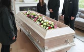 familie rondom een uitvaartkist met bloemen tijdens een stille crematie in besloten kring.