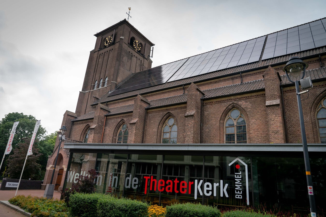 Vooraanzicht van de Theaterkerk in Bemmel, een karakteristiek kerkgebouw met moderne glazen entree en zonnepanelen op het dak – unieke locatie voor eigentijdse uitvaarten of culturele herdenkingen.