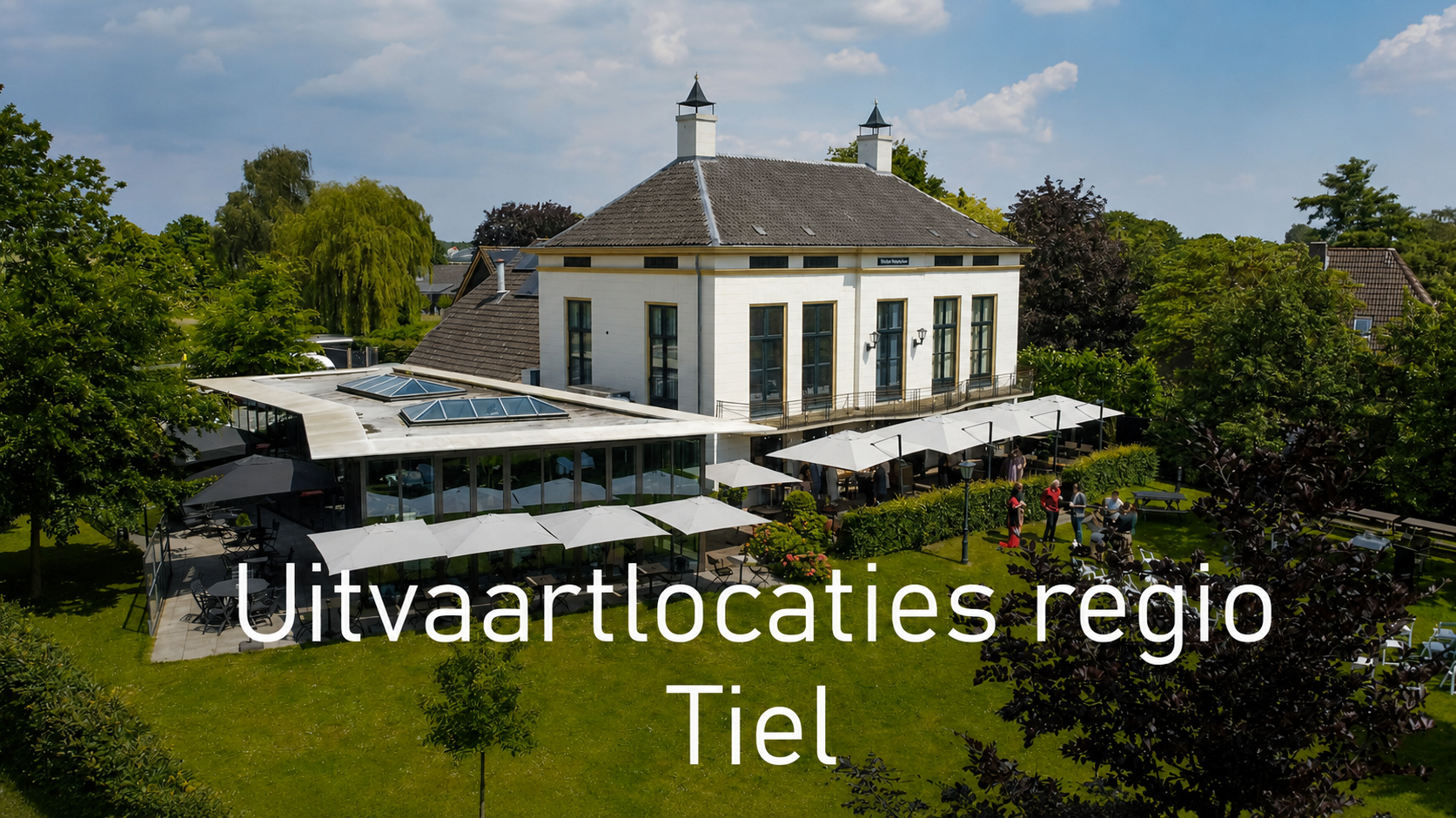 Dronebeeld van een landhuis klassiek met groen grasveld ervoor.