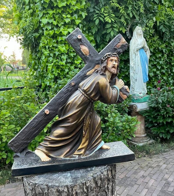 Groot antiek standbeeld Jezus draagt het kruis kruisweg
