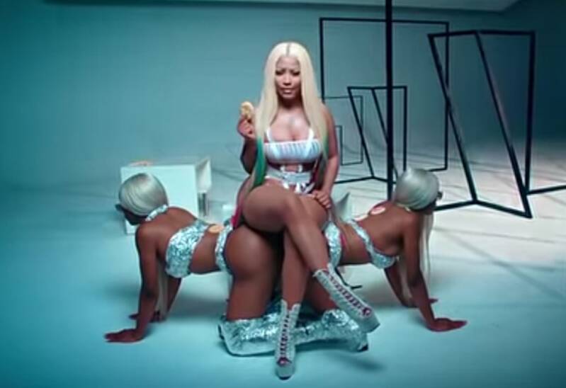 Nicki Minaj dissing Cardi B by hiring the two women to sue Cardi for her Good Form video and it shows her sitting on them as if they're the queens chair.