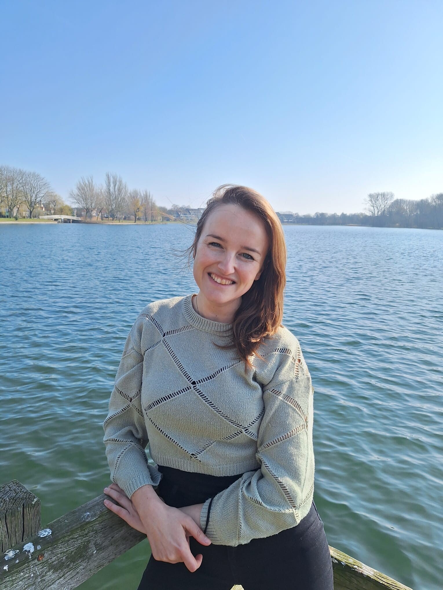 Vrouw staat op een vlonder bij het water