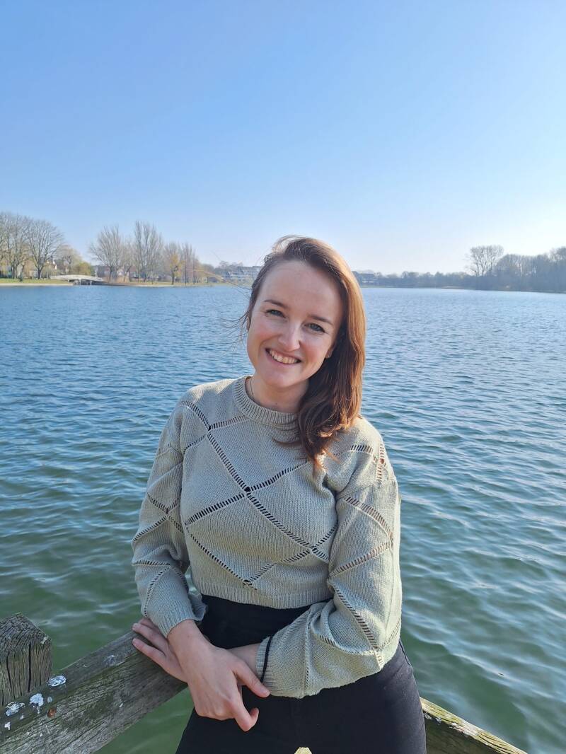 Vrouw staat op een vlonder bij het water