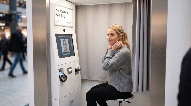 Alt-tagg (Alt-text för bild):Person som tar bilder i en modern fotoautomat för körkortsfoto i Sverige