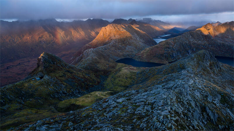 solnedgang-i-h-stfarger-med-regnboe-fra-simitinden-standard.jpg