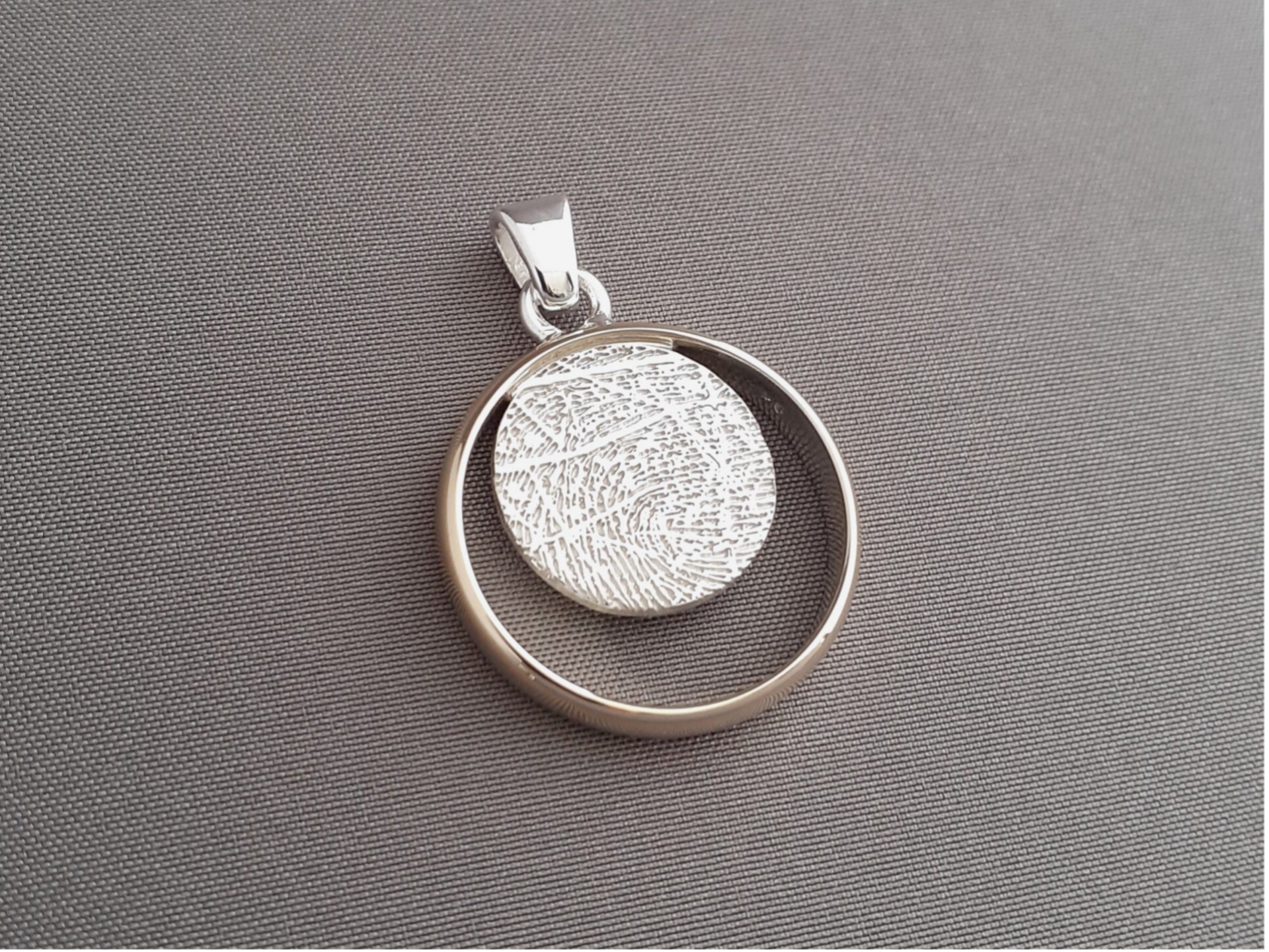 Een hanger gemaakt van een bestaande trouwring met daarin een zilver rondje gesoldeerd met vingerafdruk.