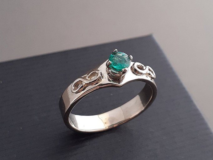 Een witgouden verlovingsring met smaragd in een chatonzetting.