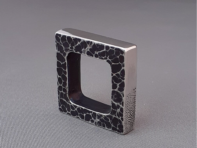 Een stoere, vierkante zilveren hanger met vingerafdruk en as. 