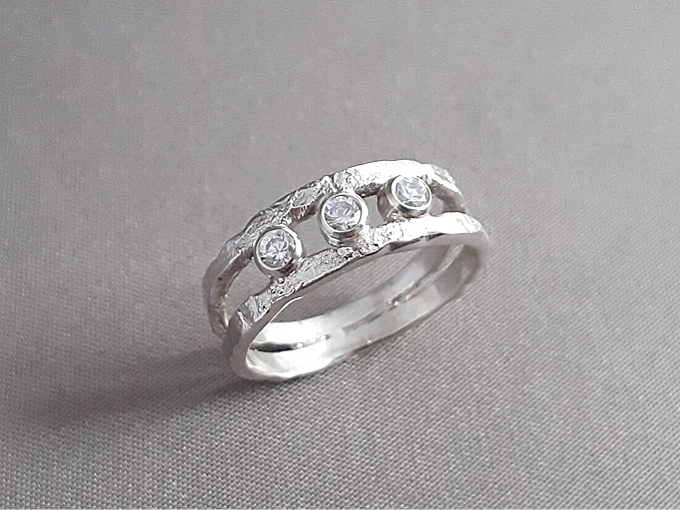 Een zilveren smeltwerk ring met 3 zirkonia's.