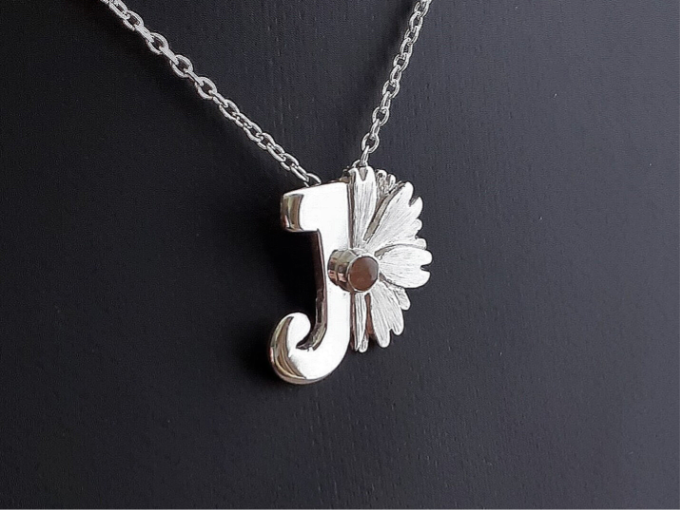 Een zilveren hanger, met een de eerste letter van het kindje, met de geboortebloem en geboortesteen. 