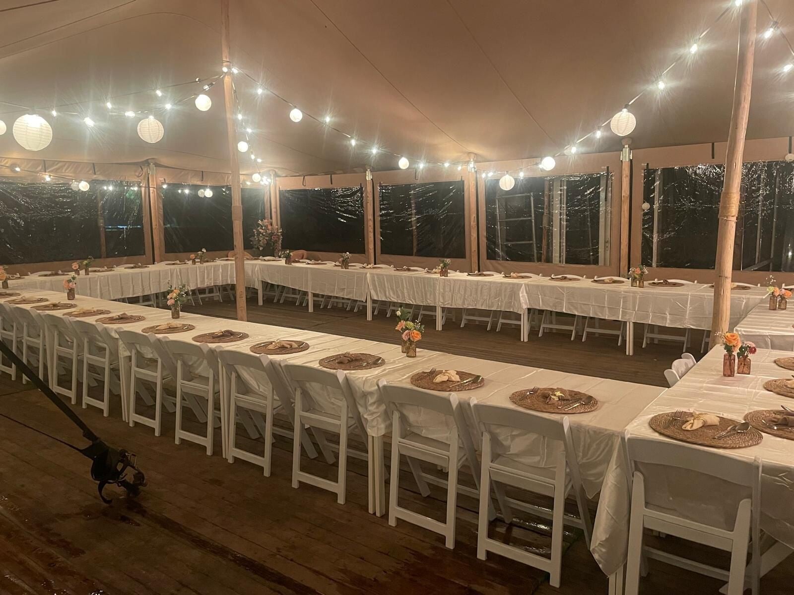 Bruiloftsdiner onder een stretchtent met witte stoelen, vlondervloer en warme prikkabelverlichting