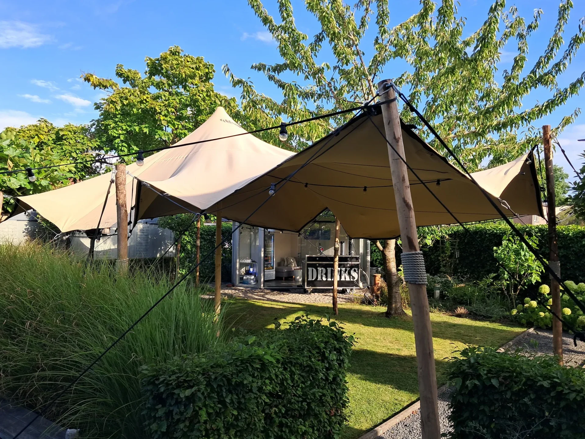 Stretchtent met houten palen en prikkabels in de tuin, gefotografeerd door Anke Zeldenthuis