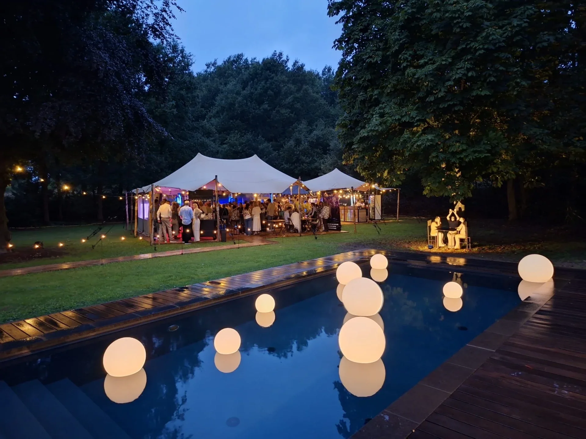 Gekoppelde stretchtenten met feestgasten en verlichting naast een zwembad, foto van Martin van der Wardt