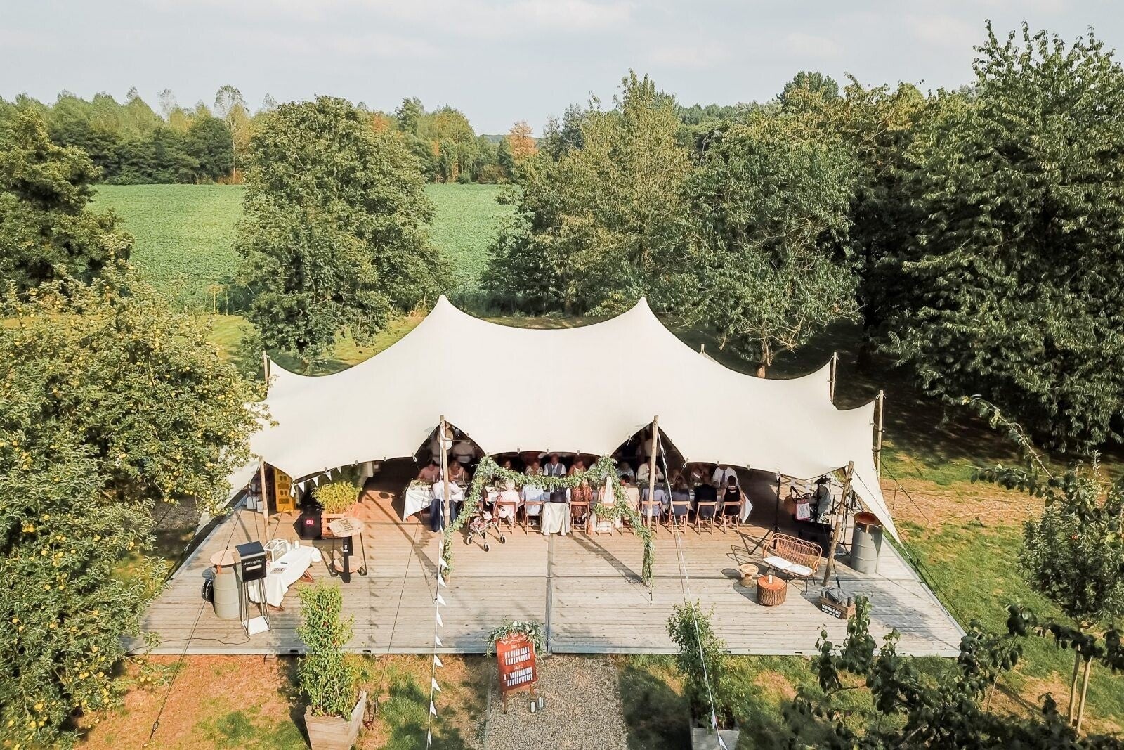 Ruime stretchtent voor een bruiloft met dinertafels, loungehoek en houten vloer
