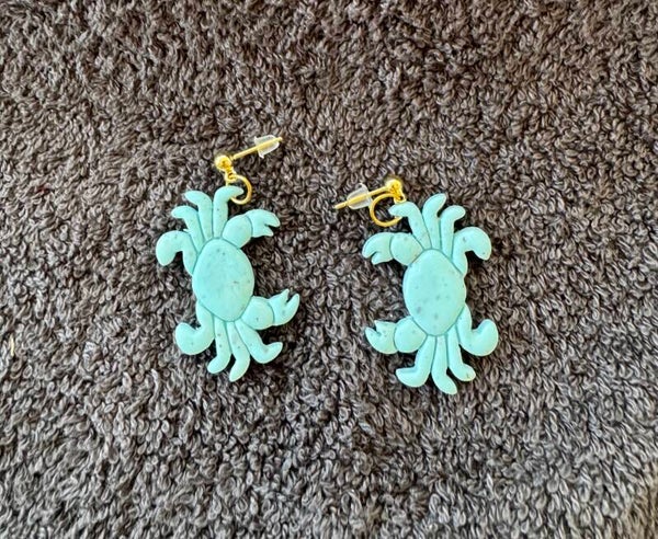 Boucles d’oreilles Crabes bleu tacheté de noir.