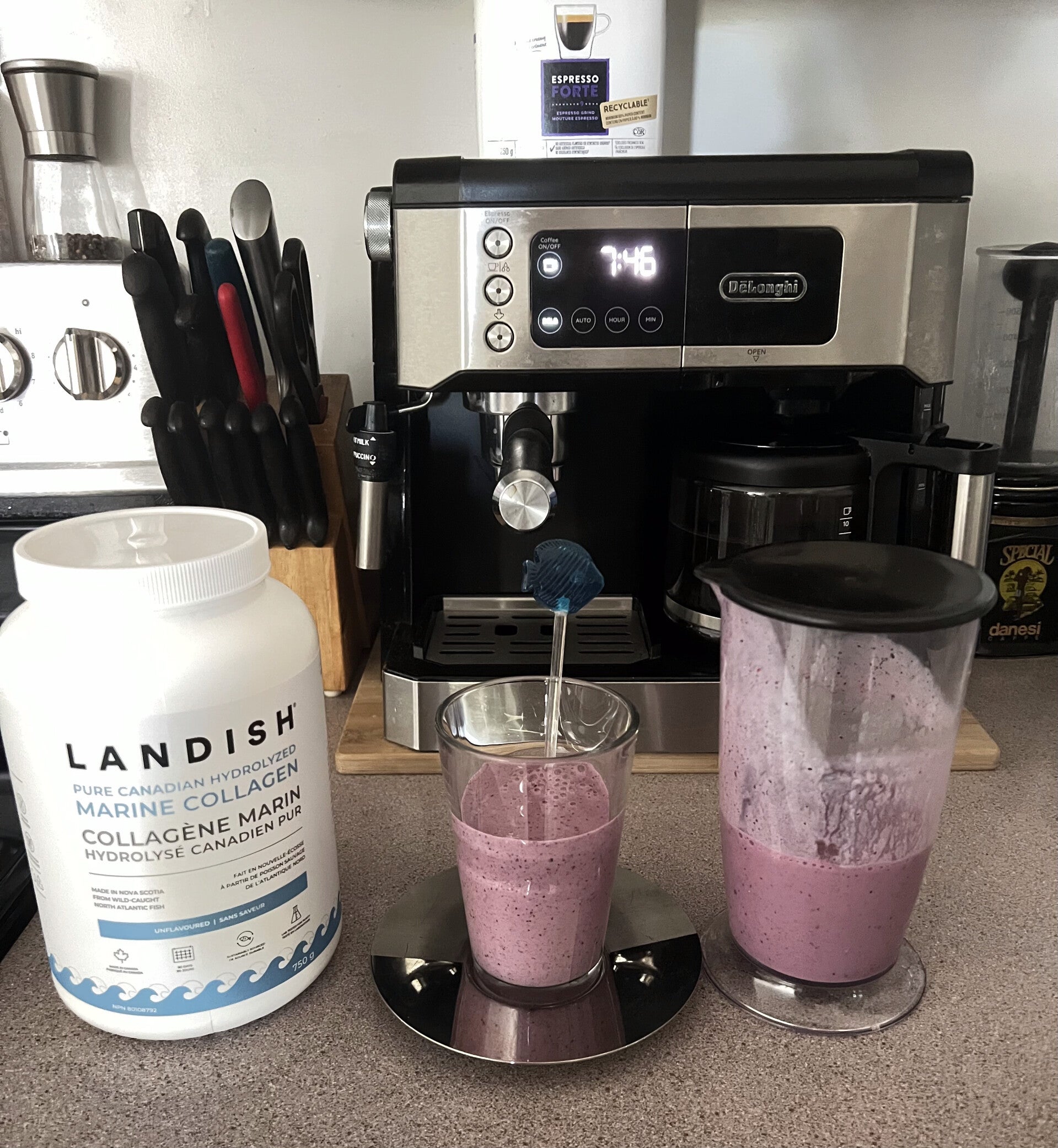 Un smoothie aux petits fruits violet servi dans un verre avec une paille et dans un pichet de mélangeur, posé sur un comptoir de cuisine à côté d'un pot de collagène marin pur Landish.