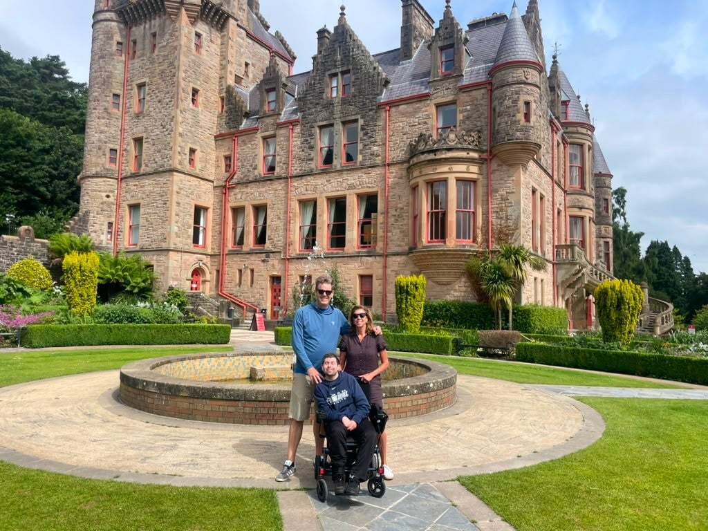 A family of three posing in front of Belfast Castle. 