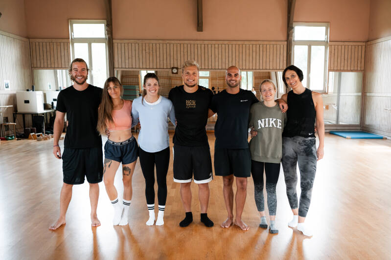 Gruppe eines Handstand Workshops in einer Turnhalle mit Holzboden
