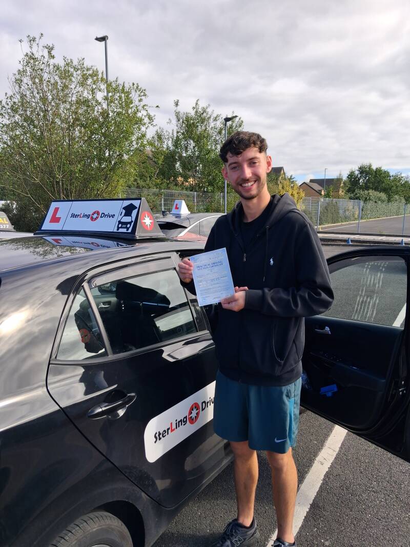 Happy pupil holding driving test pass certificate next to Sterling Drive car