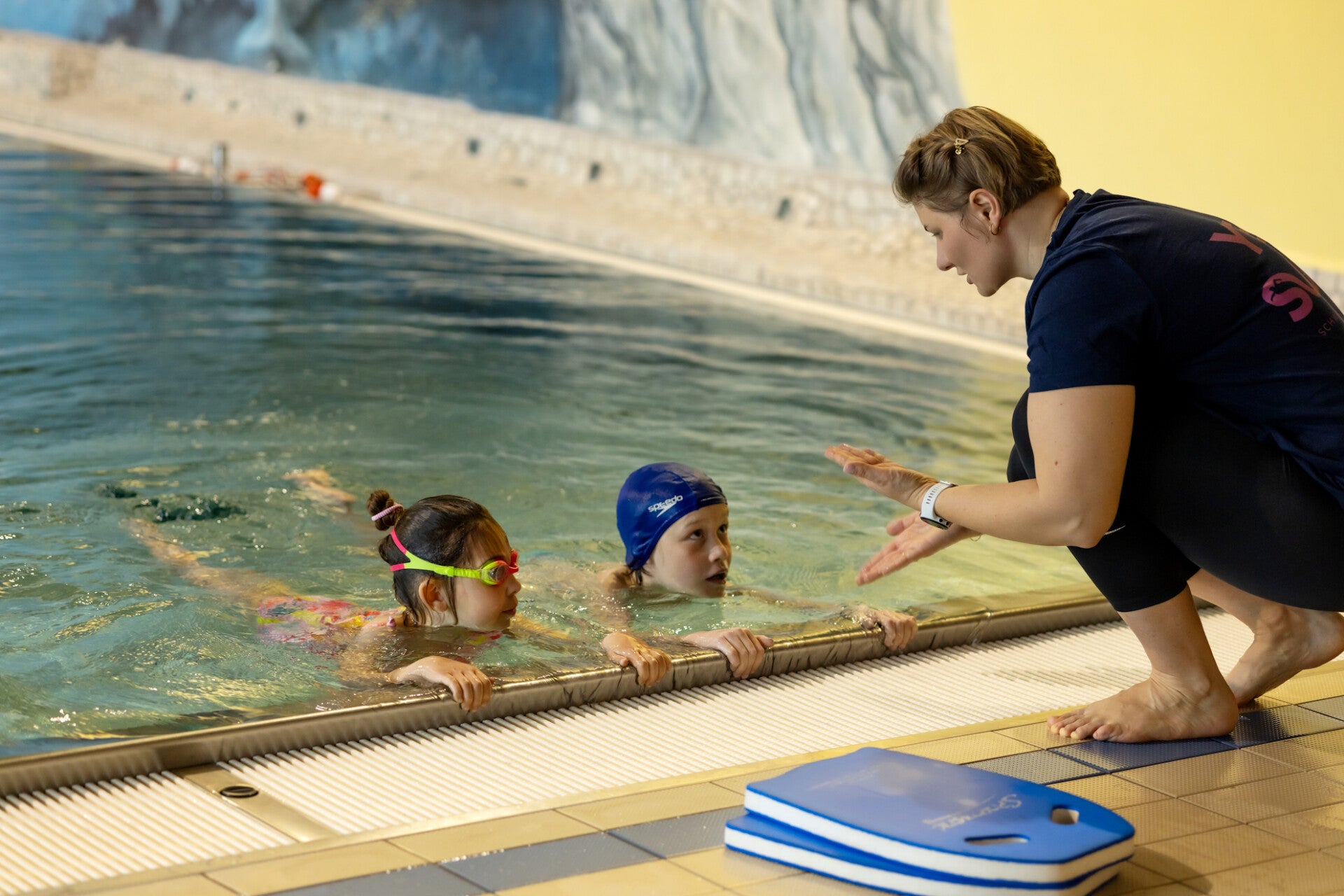 Schwimmlehrerin von yes.swim Schule erklärt den Kindern, wie man die Beine bewegen soll
