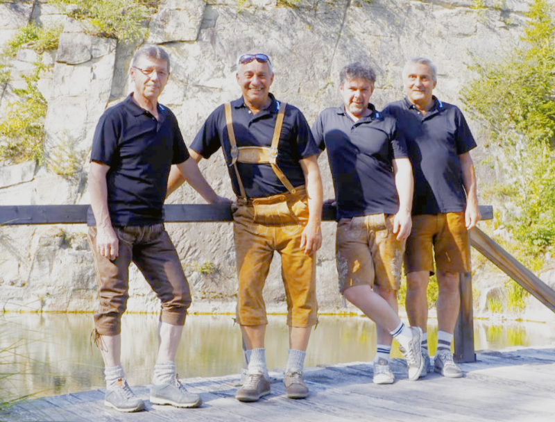 Biggobello Musikgruppe aus Niederbayern – vier Musiker in bayerischer Tracht beim Gruppenfoto in idyllischer Landschaft