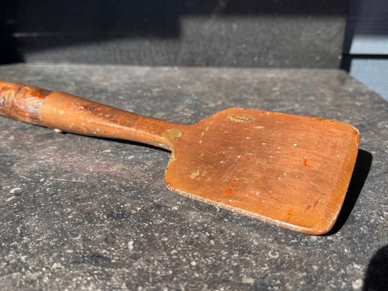 Top view of antique copper spatula with worn wooden handle - French hotel kitchen