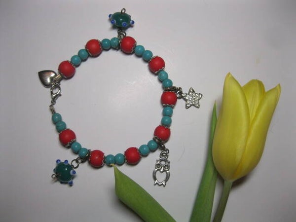 Bracelet en perles rouges et turquoise avec plusieurs breloques