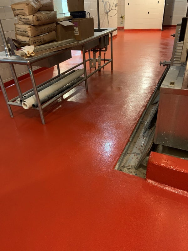 Red solid-color epoxy floor with cove base by ProResin Flooring Solutions