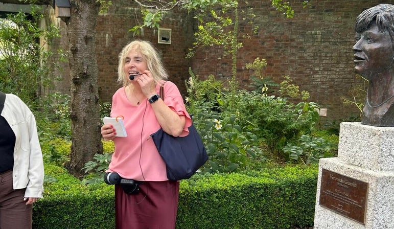 Tour Guide addressing a group and standing beside the bust of Veronica Geiran in Dublin Castle Park