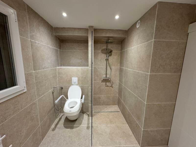 Après rénovation : douche vitrée et nouveaux revêtements aux tons minéraux