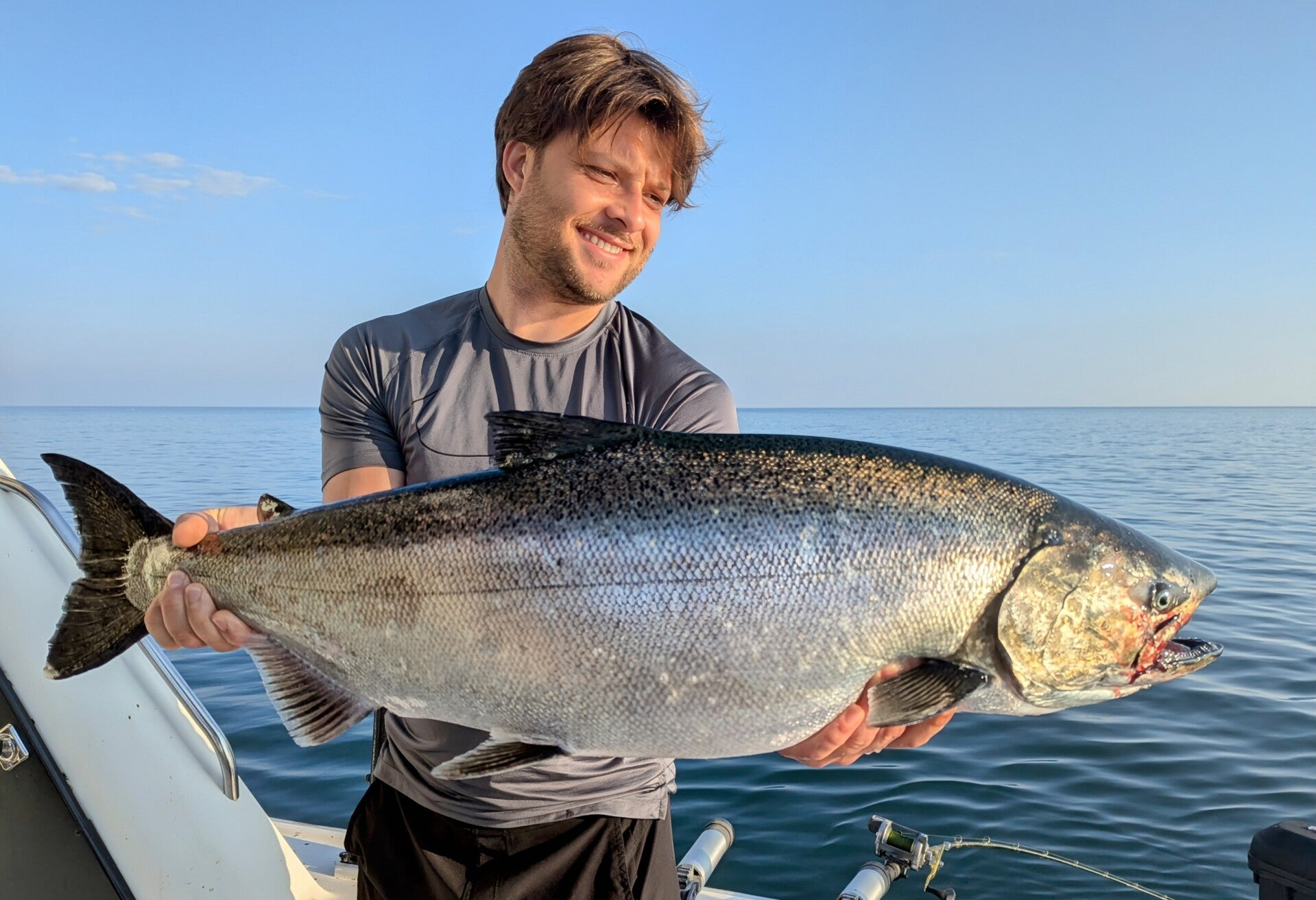 Another happy customer holding a monster Chinook salmon on a Lake Ontario fishing charter 