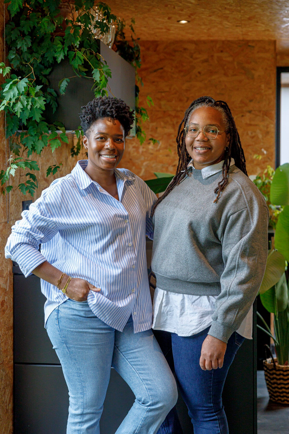 Twee vrouwen staan lachend naast elkaar geposeerd. 