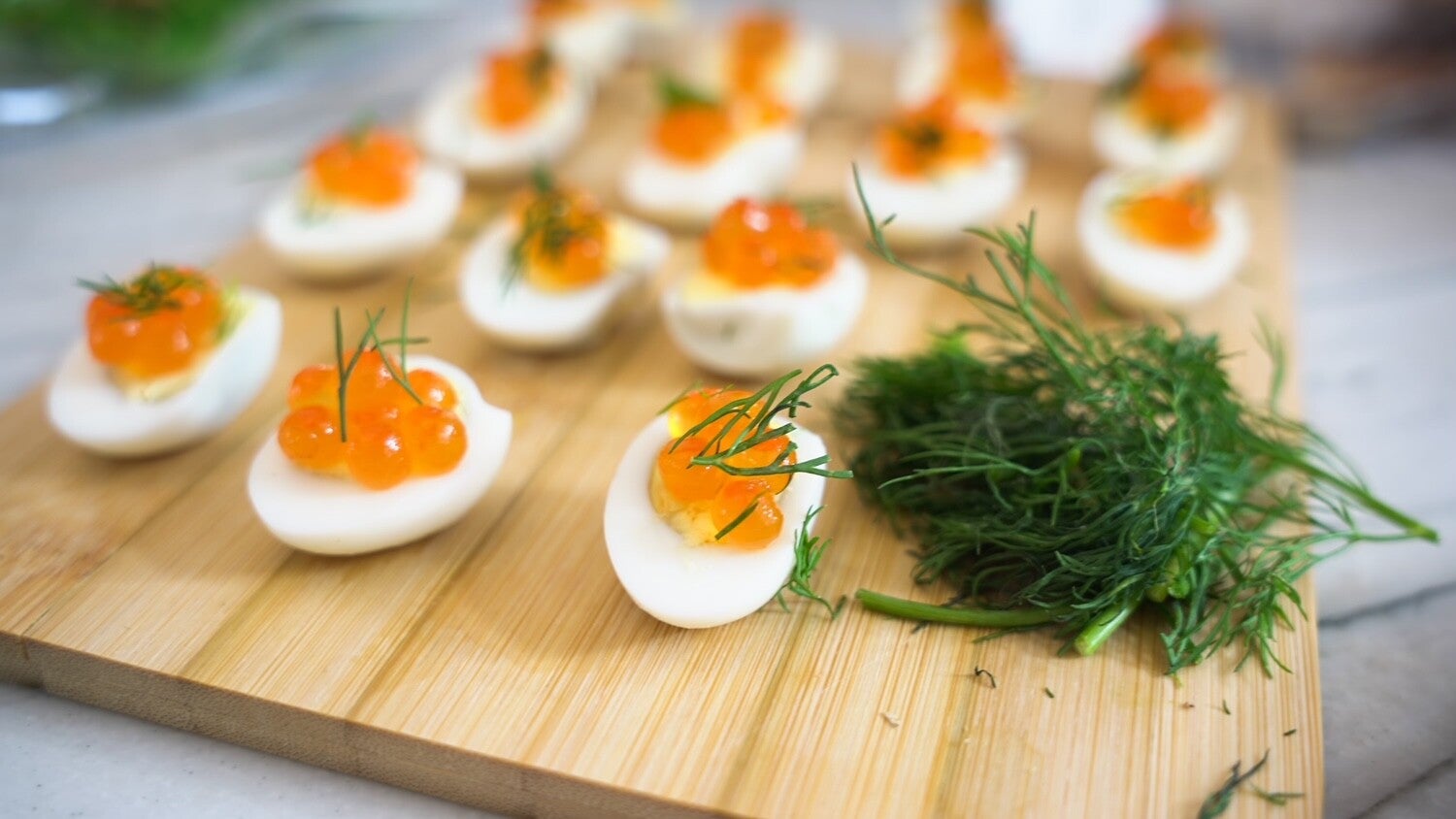 qual eggs served on a wooden plank topped with salmon rowe and decorated with dill