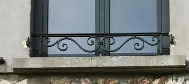 Garde-corps de fenêtre Diana en fer forgé thermolaqué avec volutes symétriques.