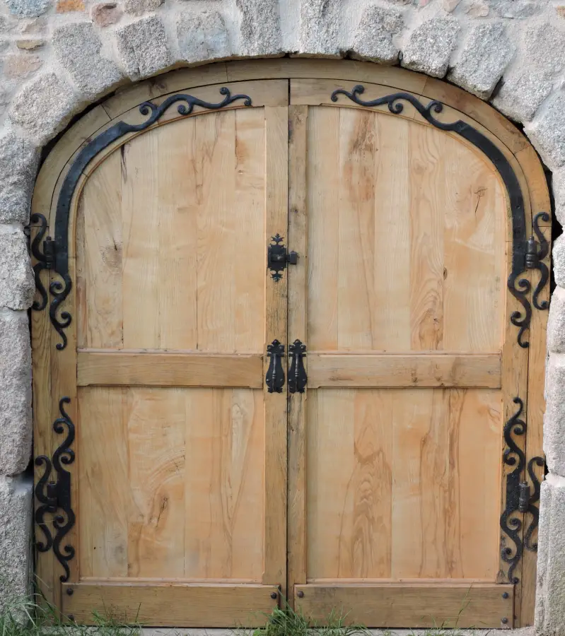 Porte en bois massif équipée de pentures décoratives en fer forgé artisanal